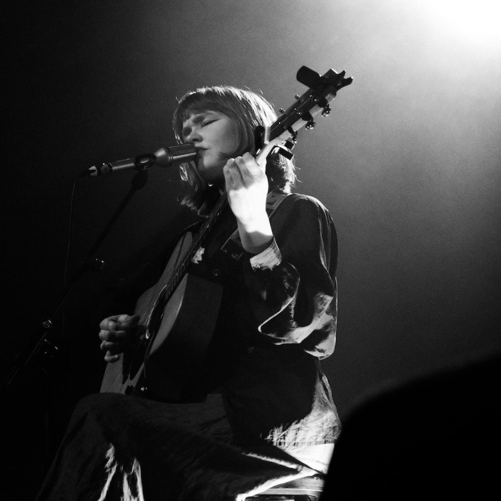 Sophie de Munnik op gitaar en aan het zingen op een podium